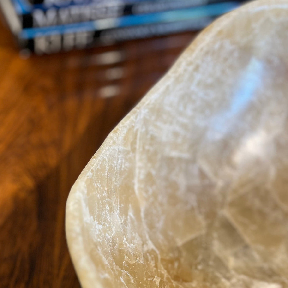 Polished onyx bowl with natural fissures on a wooden surface